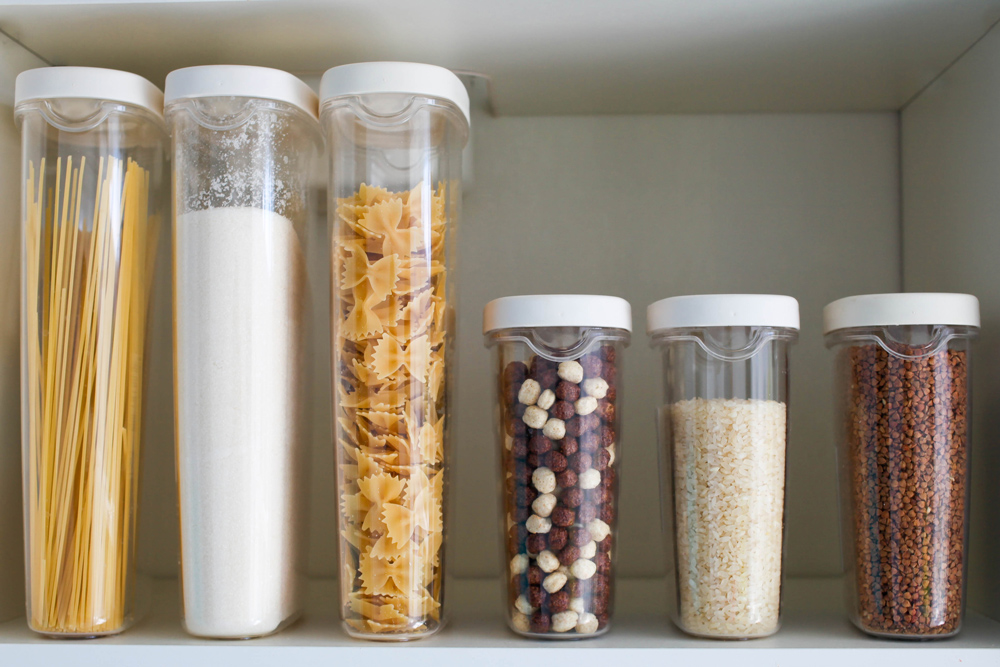 Healthy food items stored in clear containers on pantry shelf